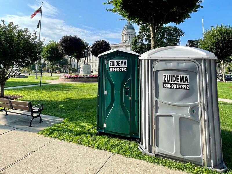 Two portable toilets on grass, available for events in New York and New Jersey